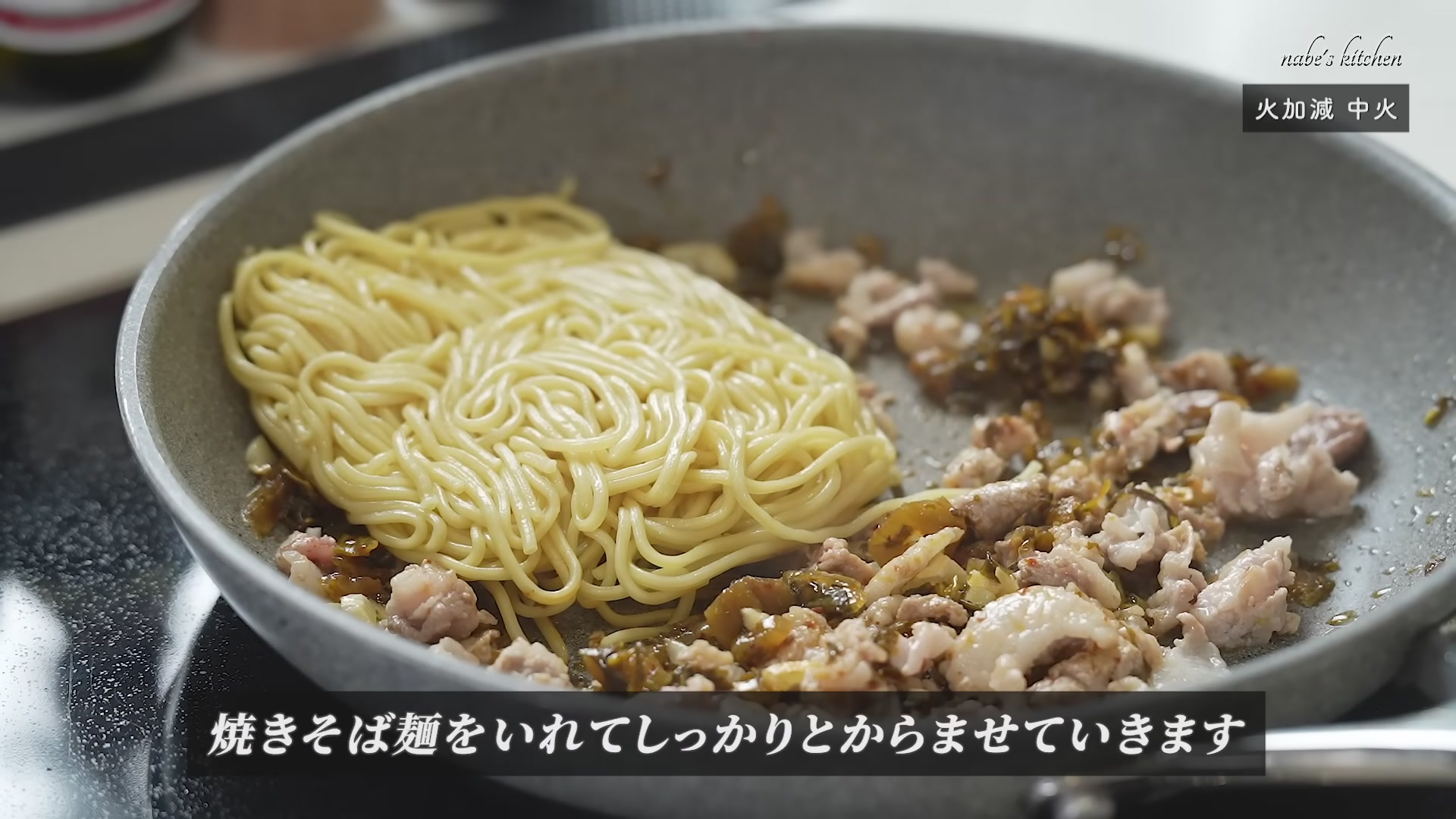 手順6：豚肉に火が通ったら、温めておいた焼きそば麺を加え、ガーリックオイルを全体に絡める