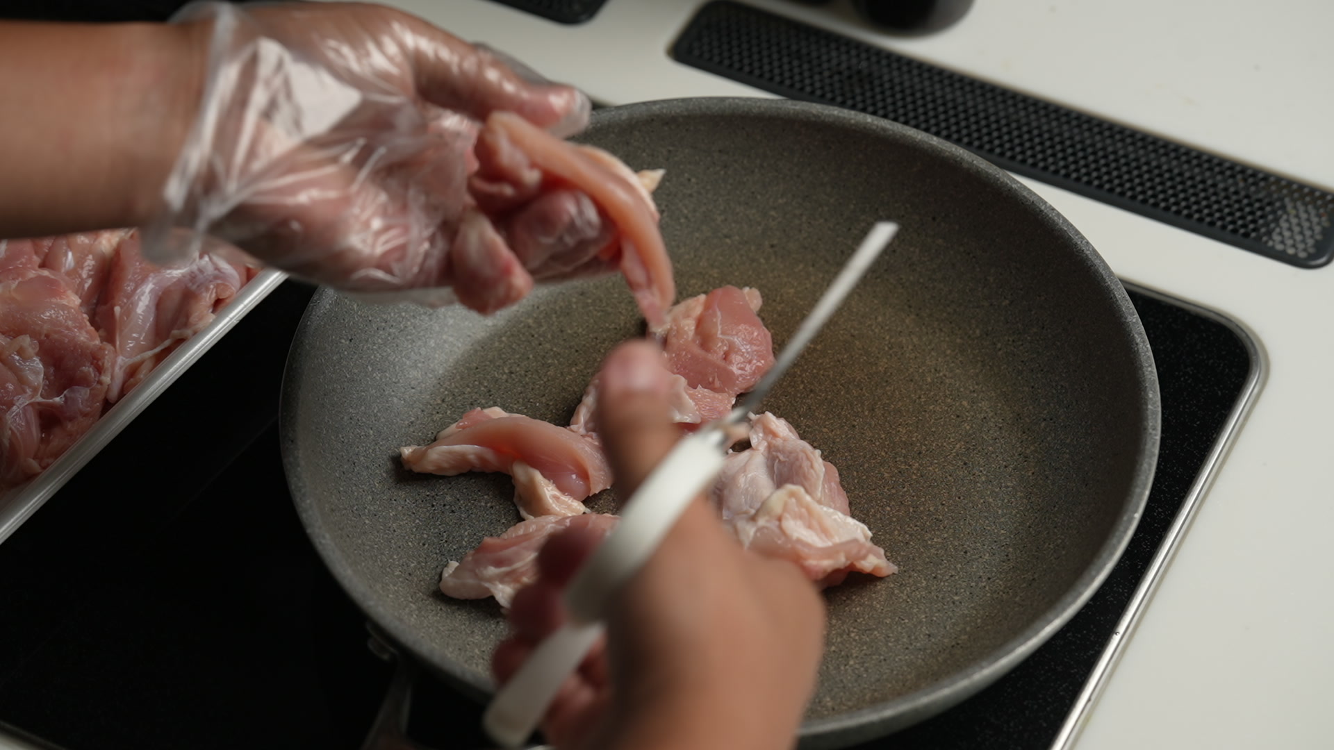 手順1:鶏もも肉をキッチンバサミで皮ごと一口大に切り、フライパンに直接入れる(包丁・まな板は使わない)